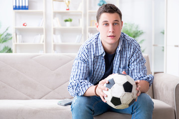 Young man student watching football at home