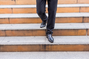 Businessman legs taking step on a lower level on a stairs - bad business investment decision concept