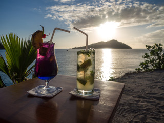 Colourful Cocktail Drinks with Straws Looking at Landscape View of Tropical Ocean Island Sunset on Beach