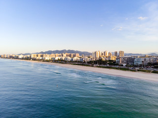 Naklejka na ściany i meble aerial landscape photo of Barra da Tijuca beach , with waves crashing on beach during sunrise, with the beachfront buildings in the background