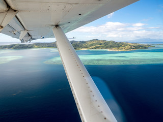 Aerial Inside Seaplane View of Tropical Island and Deep Blue Colourful Ocean Reef