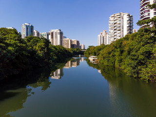 Fototapeta na wymiar Aerial view of Marapendi canal in Barra da Tijuca on a summer day. Tall residential skyscrapers on both sides, with green vegetation