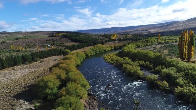 Aerial drone scene of Pulmari river with rocks, steppe, mountains and yellow trees in autumn and willow tree, road and a truck Camera moving forwards.