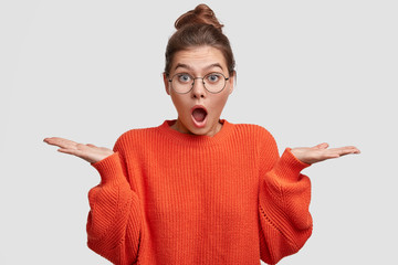 Photo of shocked young European female with stunned doubtful expression, keeps mouth widely opened,...