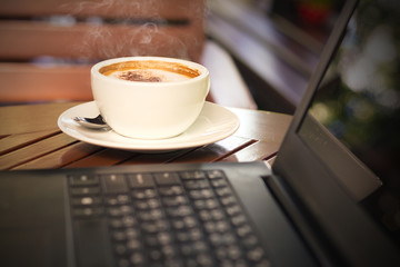 hot coffee and laptops on wooden table