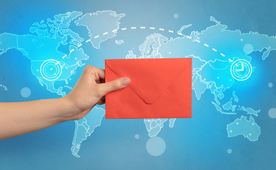 Female hand holding coloured and white envelope with blue map on the background

