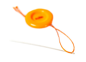 orange button with thread and needle