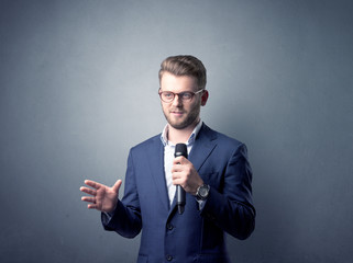 Businessman speaking into microphone with blue background