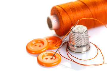 Needle with orange thread and buttons