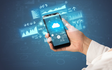 Female hand using smartphone with financial tracking concept illustrated by graphs and symbols