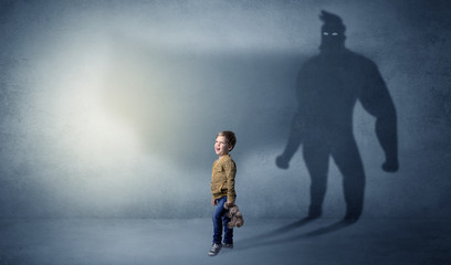 Cute kid in a room with plush on his hand and hero shadow on his background
