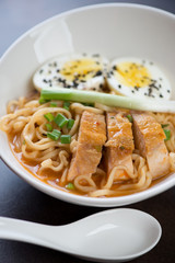 Close-up of ramen noodles with roasted chicken, egg and green onion, selective focus, vertical shot