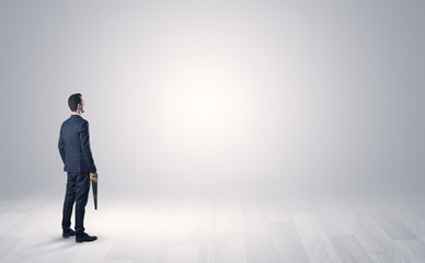 Fototapeta premium Man standing with his back in an empty room with object in his hand