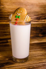 Gingerbread man in a glass of milk on wooden table