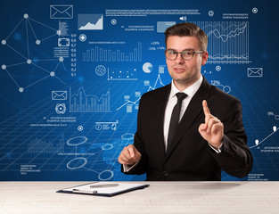 Young handsome businessman sitting at a desk with blue charts and data behind him