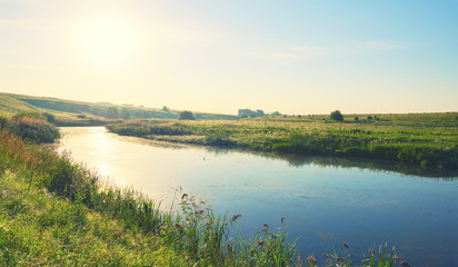 Sunny summer landscape with river, green hills, meadows and pastures at sunrise.River Upa in Tula region, Russia.