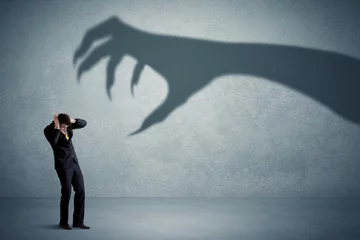 Fotobehang Business person afraid of a big monster claw shadow concept on background © ra2 studio