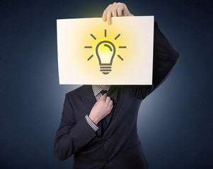 Young businessman hiding behind a lightbulb drawn on paper