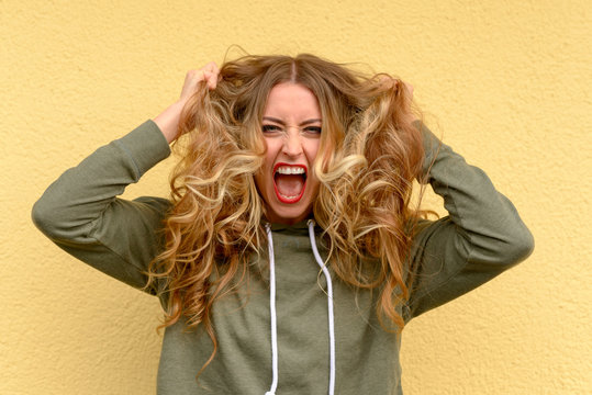 Frustrated blond woman tearing at her long hair