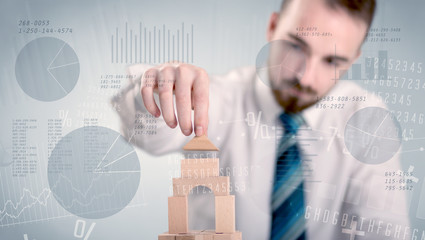 Young handsome businessman using wooden building blocks with data and numbers around him