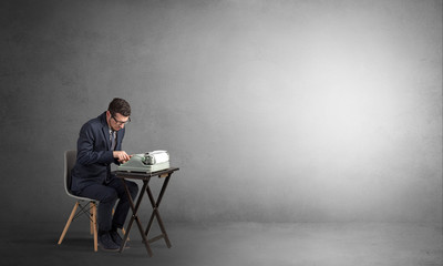 Man working hard on a typewriter in an empty space
