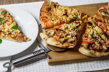 Homemade fresh pizza with tomatoes, cheese and mushrooms on table closeup