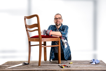 worker in blue  shirt repair old chair