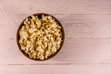 Obraz na płótnie Canvas Ceramic bowl with popcorn on wooden table. Top view