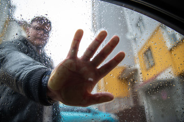 man hand palm on glass in raindrops