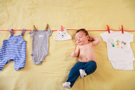 Little baby hanging with clothes on rope. Concept of funny photo session for babies.