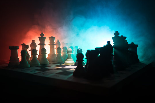 Chess board game concept of business ideas and competition and strategy ideas concep. Chess figures on a dark background with smoke and fog. Business leadership and confidence concept.