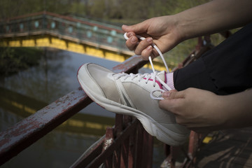 young girl tying laces on white shoes before a jog, the concept of sport