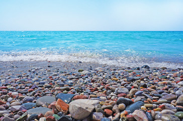Seascape and coastal pebbles in sunny day. Marine panoramic view.