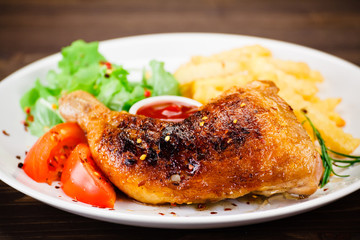 Roasted chicken leg with french fries on wooden background