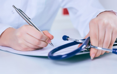 Close up of a female doctor filling up an application form while consulting patient. Medicine and health care concept