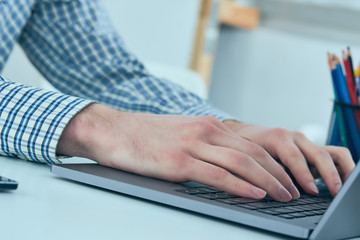 Male hands typing on laptop keyboard. Young man using laptop computer. Business working concept.
