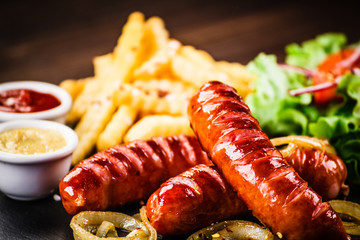 Grilled sausages, French fries and vegetables