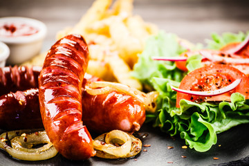 Grilled sausages, French fries and vegetables