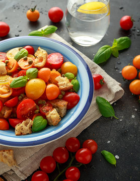 Panzanella Tomato salad with red, yellow, orange cherry tomatoes, capers, basil and ciabatta croutons. summer healthy food.