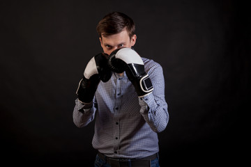 Fototapeta na wymiar Dark-haired man in a plaid shirt with boxing gloves on his hands in stance on black isolated background