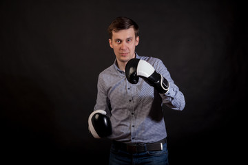 Dark-haired man in a plaid shirt with boxing gloves on his hands .stabs on black isolated background