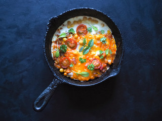 Scrambled eggs with chickpeas and tomatoes on an old pan. Top view with copy space. 