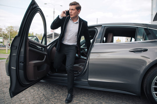Make money easily! Full length portrait of the handsome serious young businessman talking on smartphone, while leaving his car.