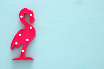 a plastic flamingo lamp with leds over blue wooden background. holiday summer concept. © tomertu