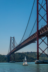 Sailboats under 25 April bridge in Lisbon
