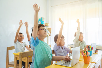 Asian school children rising hand up with smile in classroom