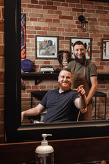 Naklejka na ściany i meble Barber and bearded man in barber shop