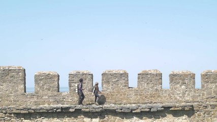 Young couple of travelers explore old fortress, tourists with backpacks in medieval castle  - Powered by Adobe