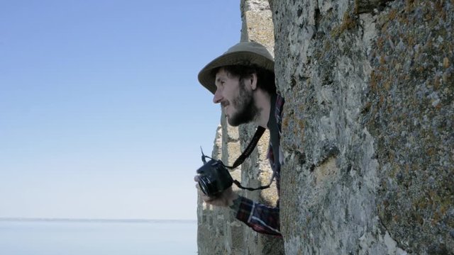 Young bearded male photographer make photo on the old tower