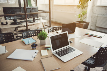 Modern laptop and exercise books situating on desk. Chairs near it in office. Design concept